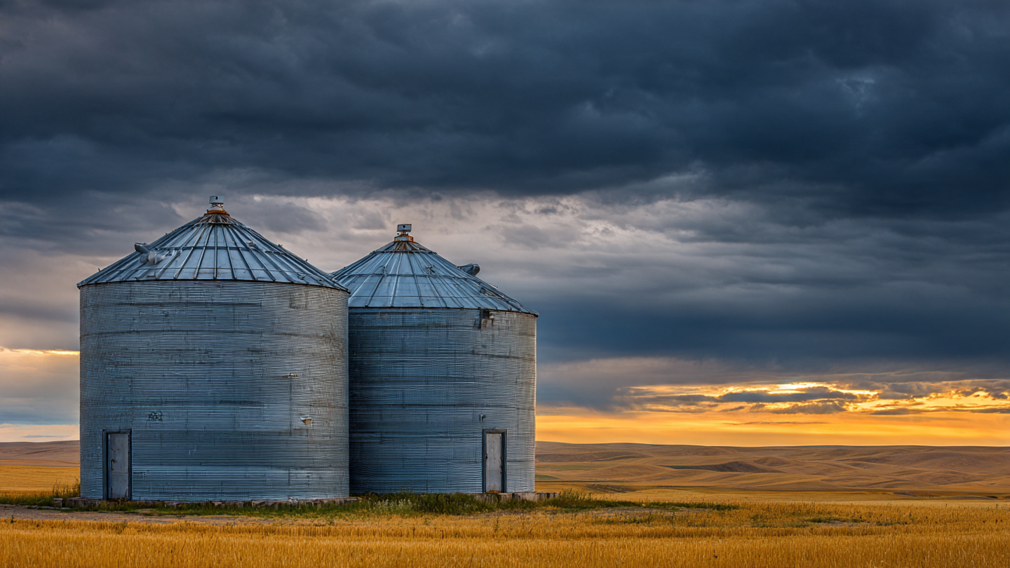 Steel grain bins on Midwestern farm at sunset